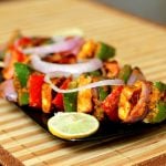 paneer tikka served with onion rings and a lemon wedge